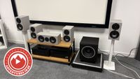 A shot of the Wharfedale Diamond 12.1i speaker package lined up in a row, with a logo in the bottom right corner which reads "Adventures in AV"