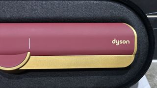 Dyson Airstrait in red and gold colourway on beige background