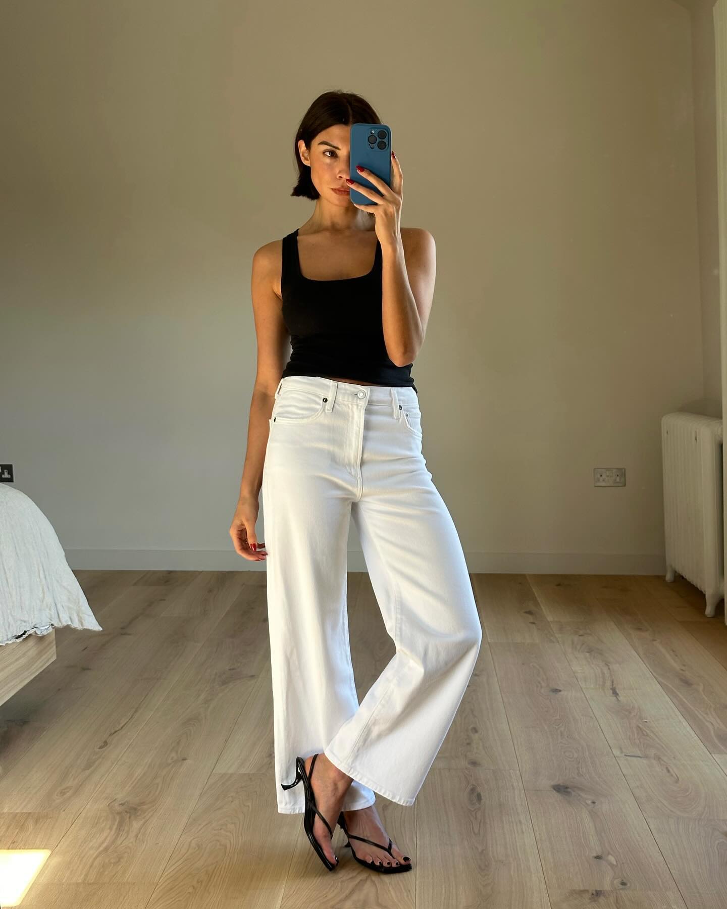 Influencer wears white jeans and black sandals.