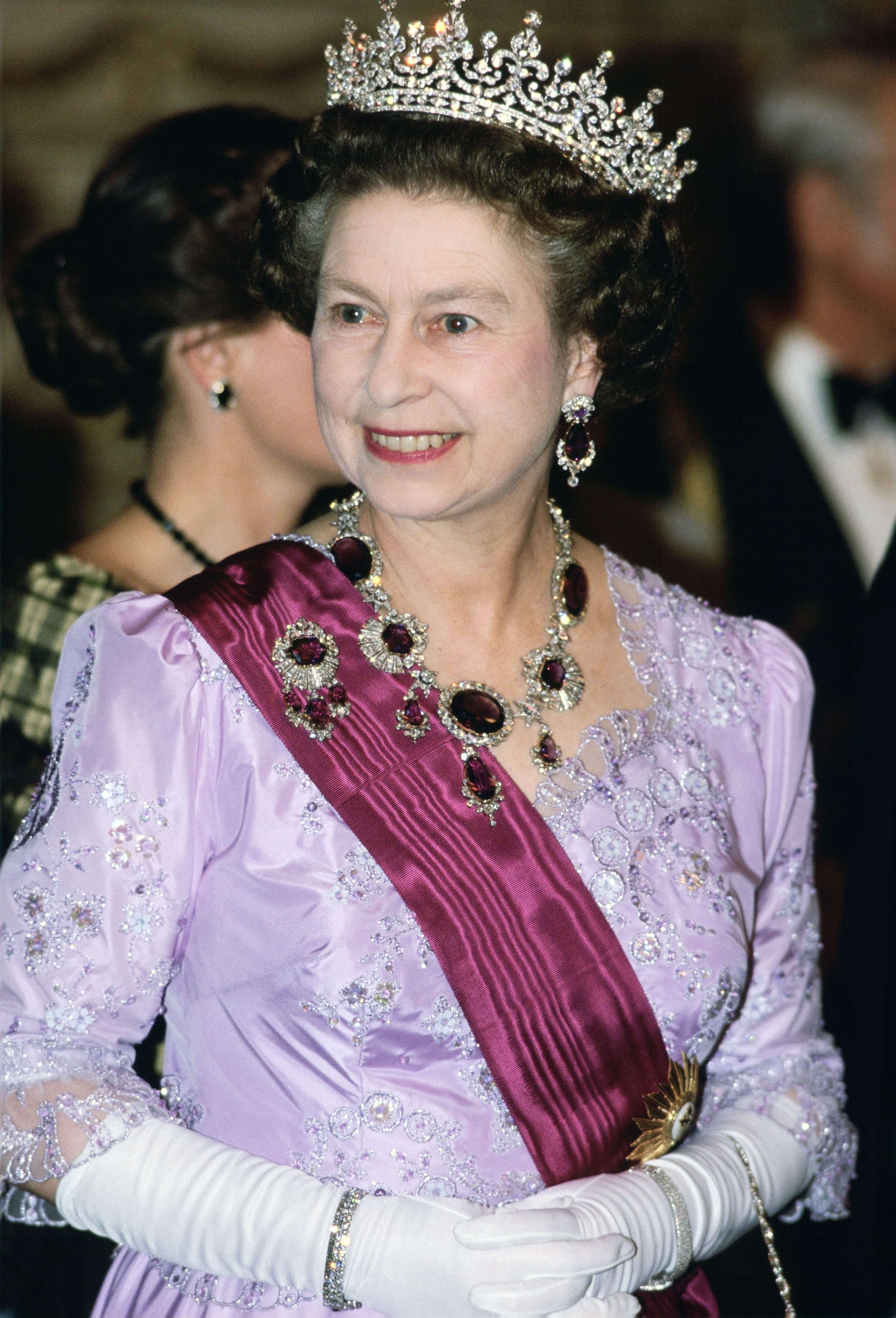 Queen Elizabeth wearing a lilac gown and a tiara with amethyst earrings and necklace