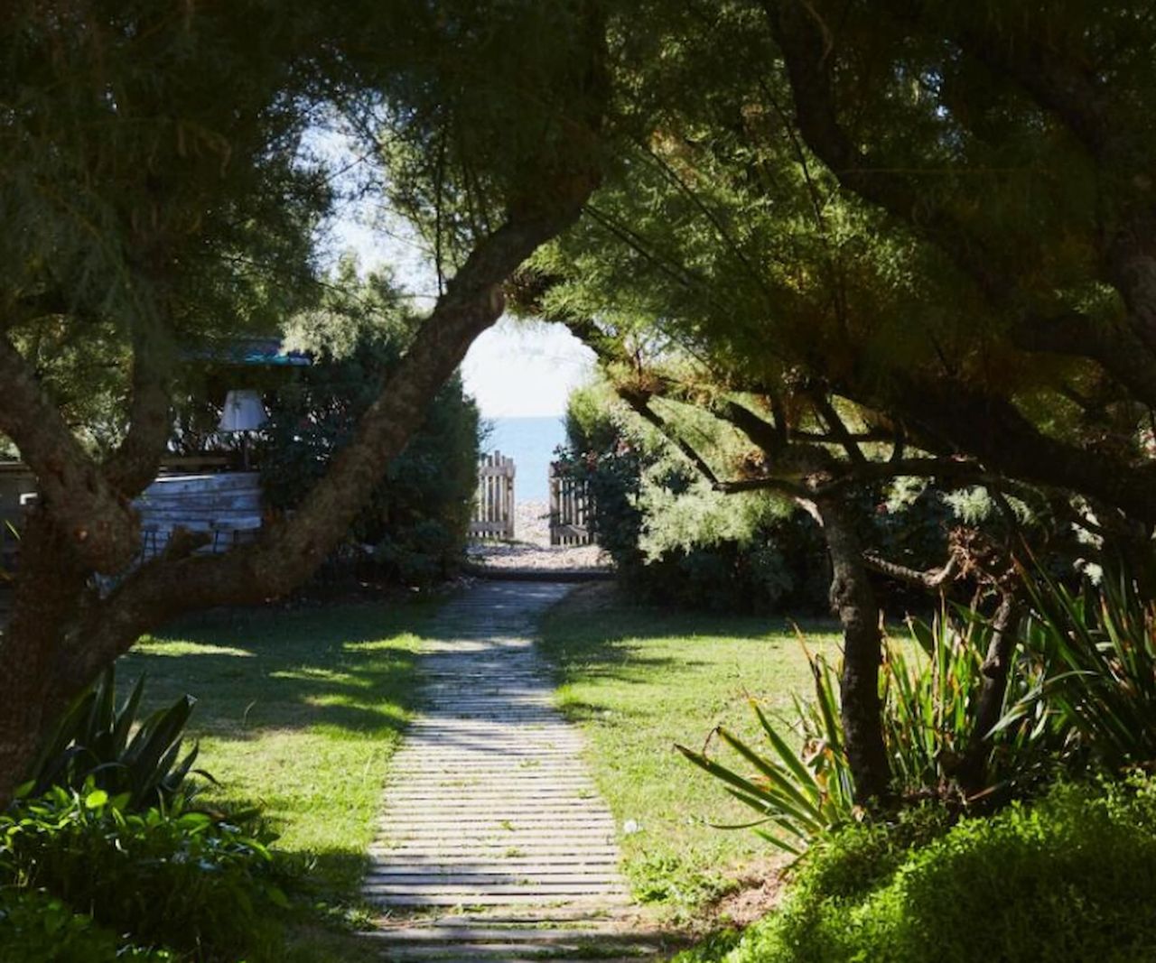 A back garden leading to a beach with a footpath