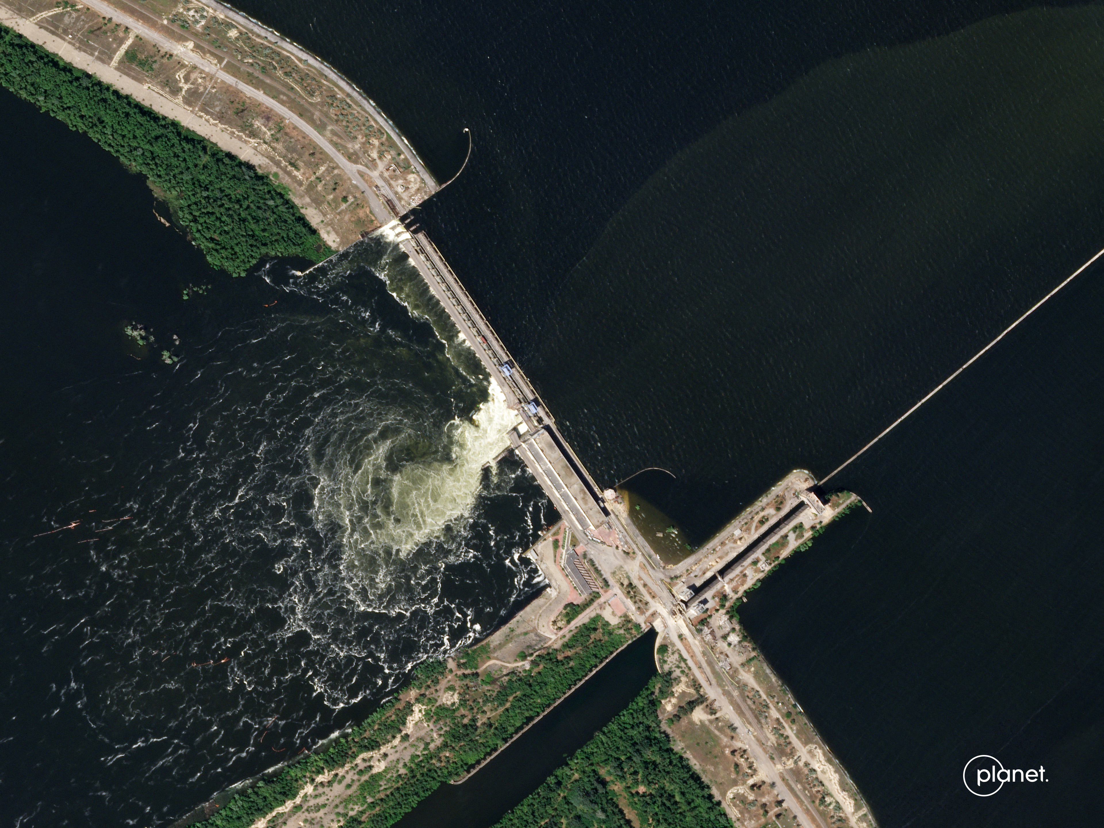 an overhead view of a river rushing through a hole in a dam