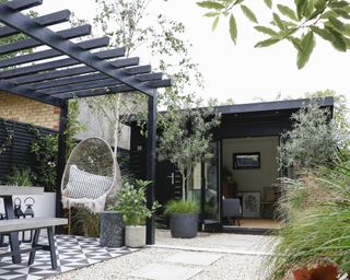 Black timber garden room with black painted pergola and hanging chair