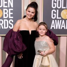 Selena Gomez in a dark purple gown with large sleeves and Gracie Elliot Teefey in a sparkly dress at the 2023 Golden Globe Awards