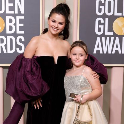 Selena Gomez in a dark purple gown with large sleeves and Gracie Elliot Teefey in a sparkly dress at the 2023 Golden Globe Awards