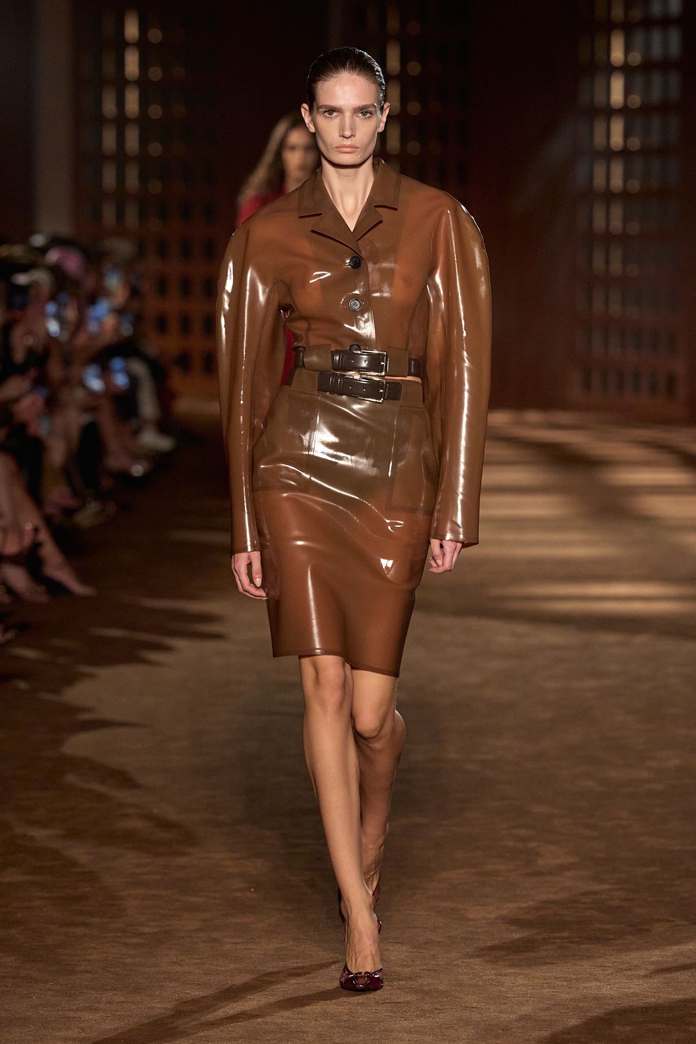 a model wears latex while walking the ferragamo spring 2027 runway.
