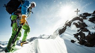 Mountaineer using ice axe at mountain summit