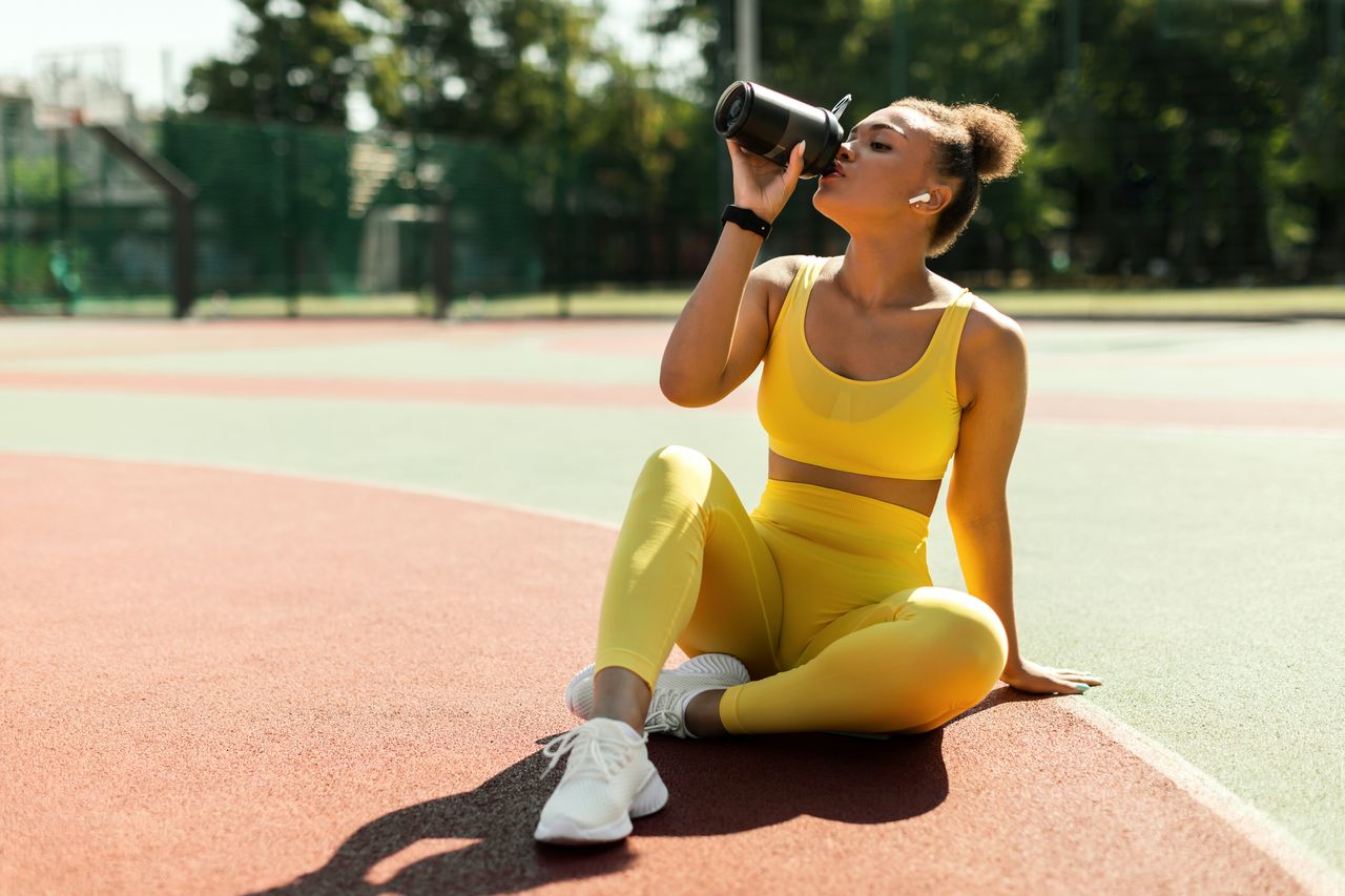 Vegan protein sources: Portrait of sporty woman in yellow sportswear drinking water