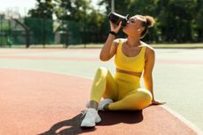 Vegan protein sources: Portrait of sporty woman in yellow sportswear drinking water