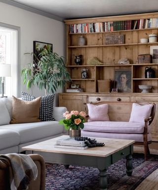 living room with wooden cabinet, white sofa, cane back bench with pink cushions, coffee table and patterned rug