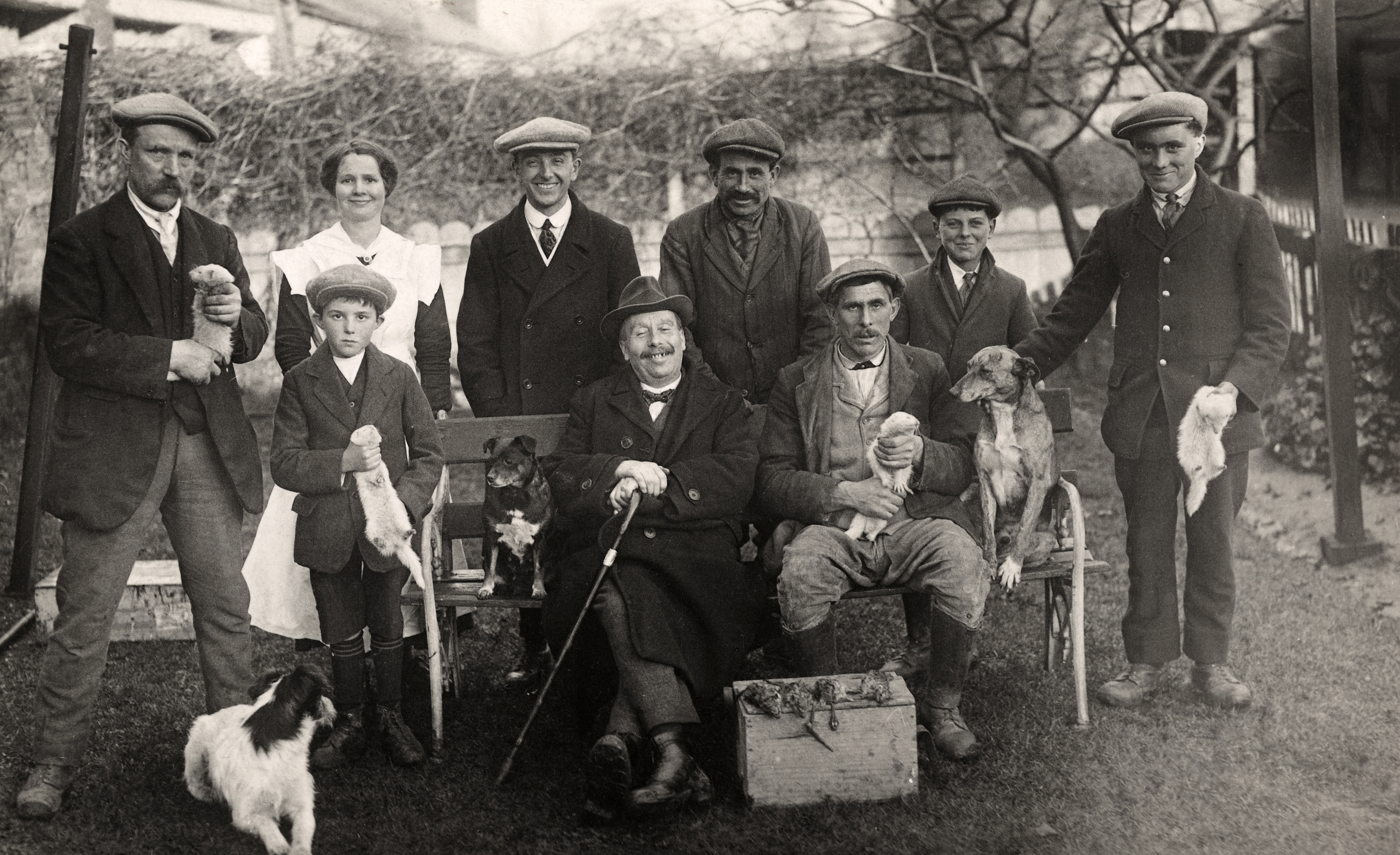 A group of people, including a woman and a boy, with their quarries after ferreting for rabbits in Cambridgeshire, circa 1910.