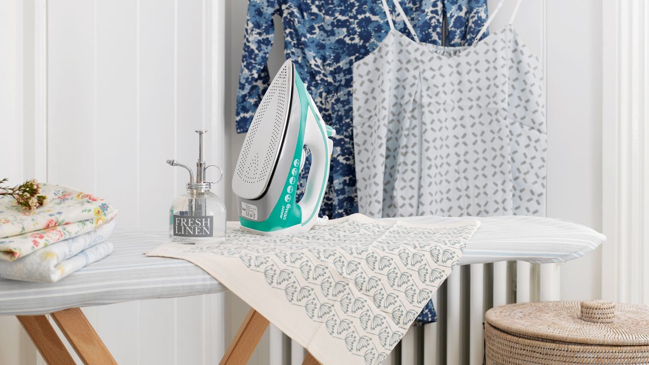 Iron on ironing board in front of laundered clothes