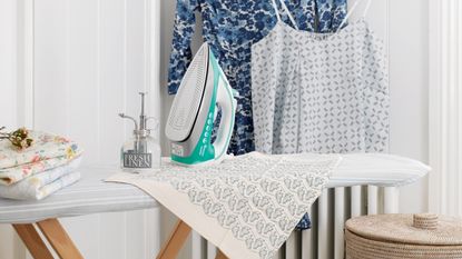 room with clothes and clothes hanger and iron with ironing table