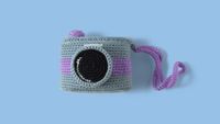 Nice retro camera, knitted with colored wool. Handmade crochet camera on blue background. Amigurumi Camera 
