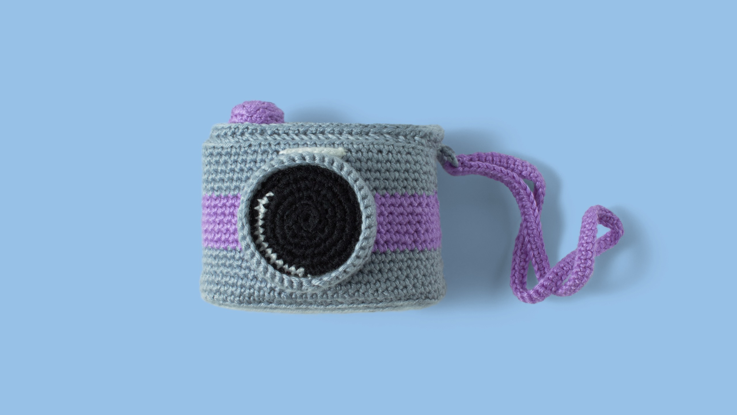 Nice retro camera, knitted with colored wool. Handmade crochet camera on blue background. Amigurumi Camera 