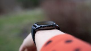 OnePlus Watch rundt et håndledd, fotografert fra siden så man ser hvor høy den er.