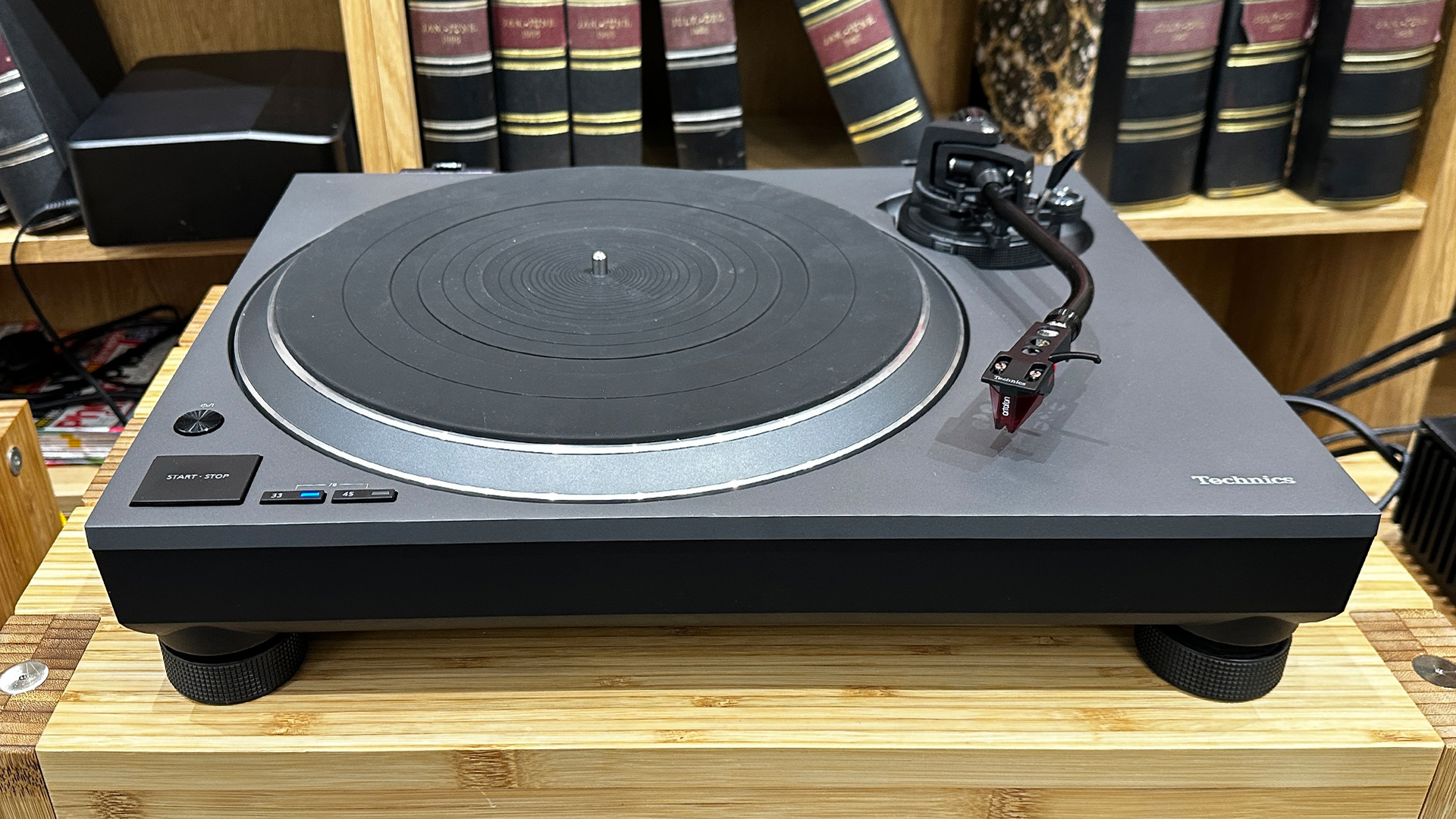 Technics SL-1500CS turntable on wooden hi-fi rack in front of bookcase