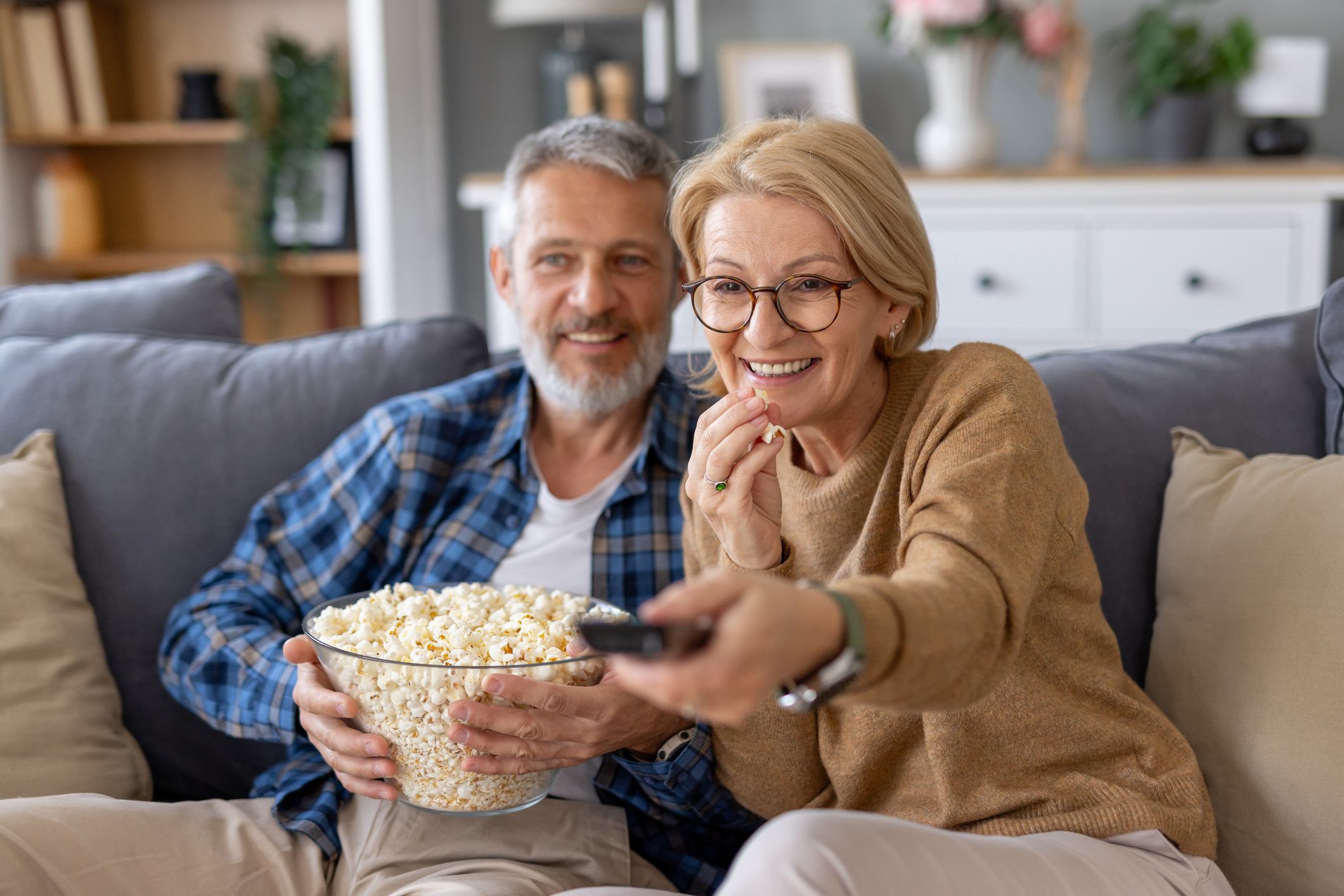 A couple laughs together while enjoying a cozy movie night at home