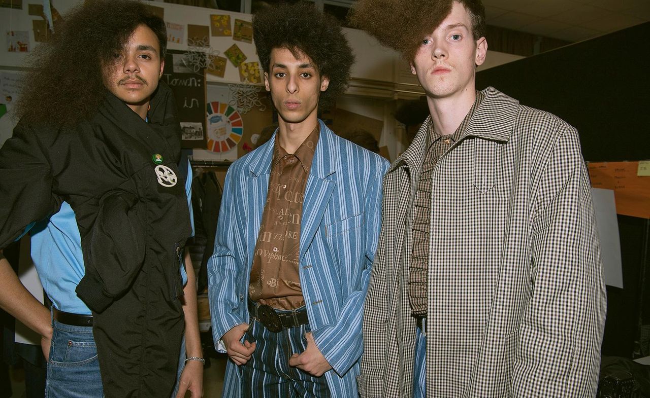 3 male models in a studio pose for the camera