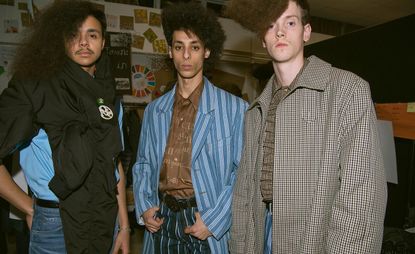 3 male models in a studio pose for the camera