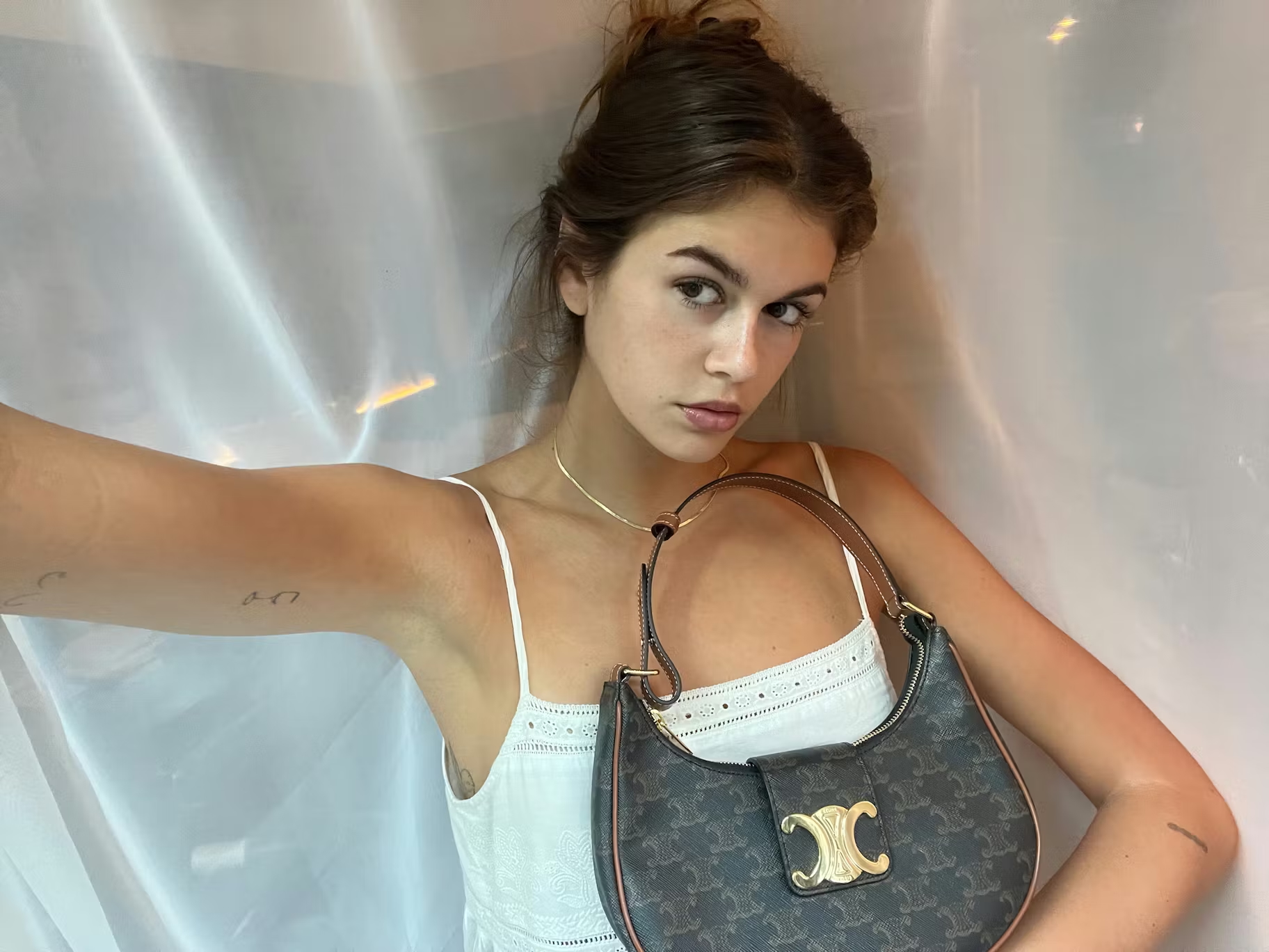 A selfie photo of Kaia Gerber in a white shirt and Celine Ava bag in brown leather