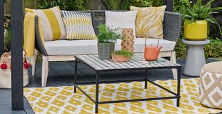 outdoor living room area with a yellow outdoor rug to support a guide for how to clean an outdoor rug