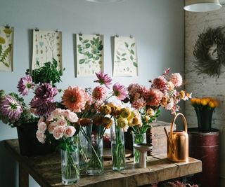 Dahlia and rose stems in vases on wooden table