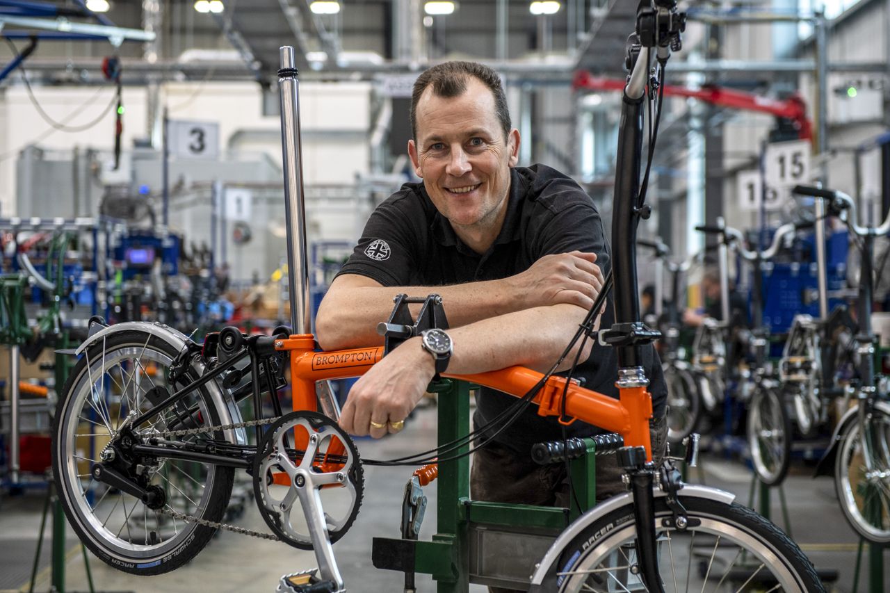 Brompton CEO Will Butler-Adams poses with an orange Brompton