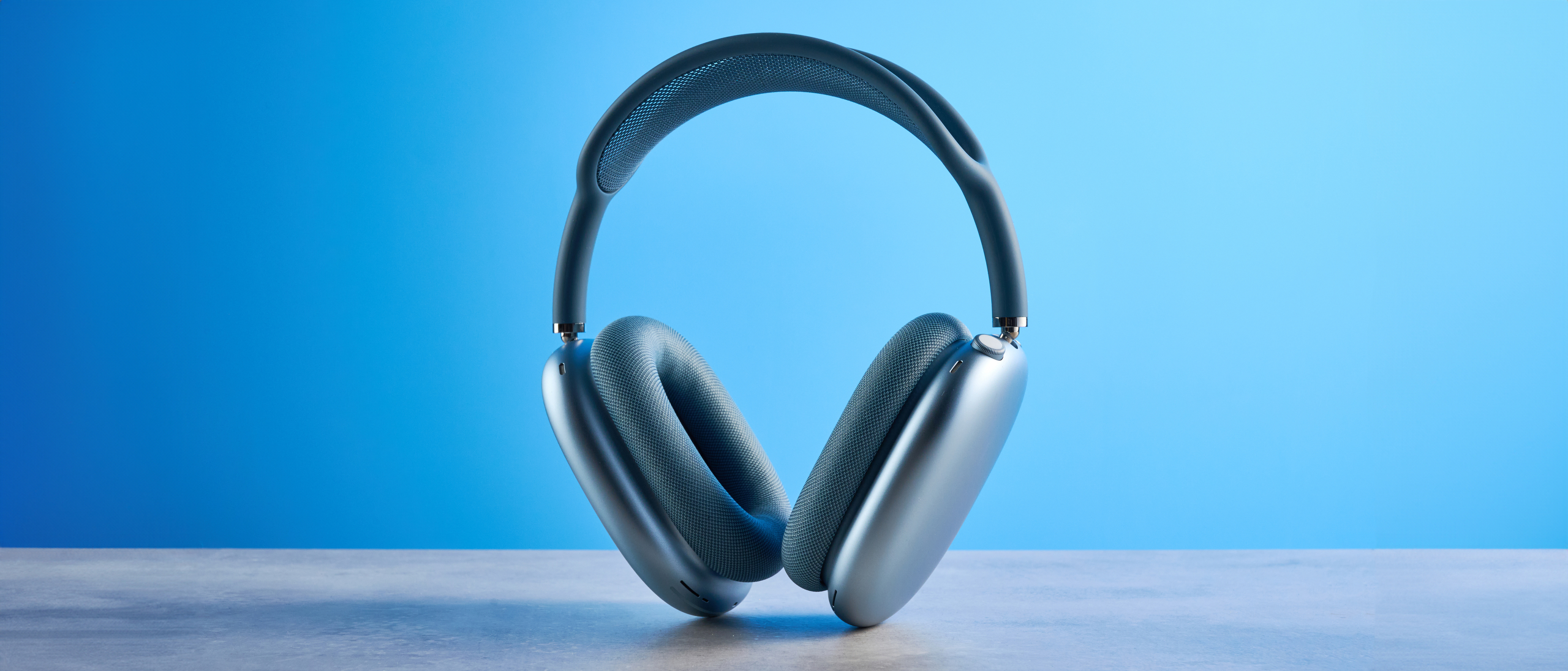 the apple airpods max 2 in blue against a blue tom's guide background, showing the shiny anodized metal ear cups, mesh headband and the fabric ear cups