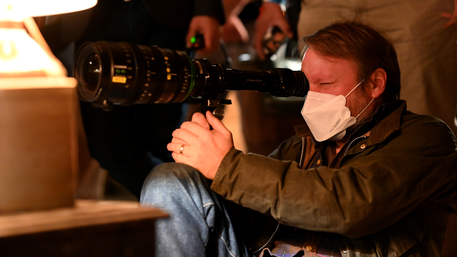 Rian Johnson looks through a camera lens as he lines up a shot in Peacock's Poker Face