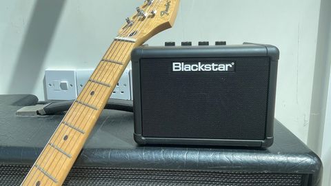 Blackstar Fly 3 sitting on top of a Blackstar Artist 15 amp with a Fender Lead II leaning against it, in front of a cream-coloured wall