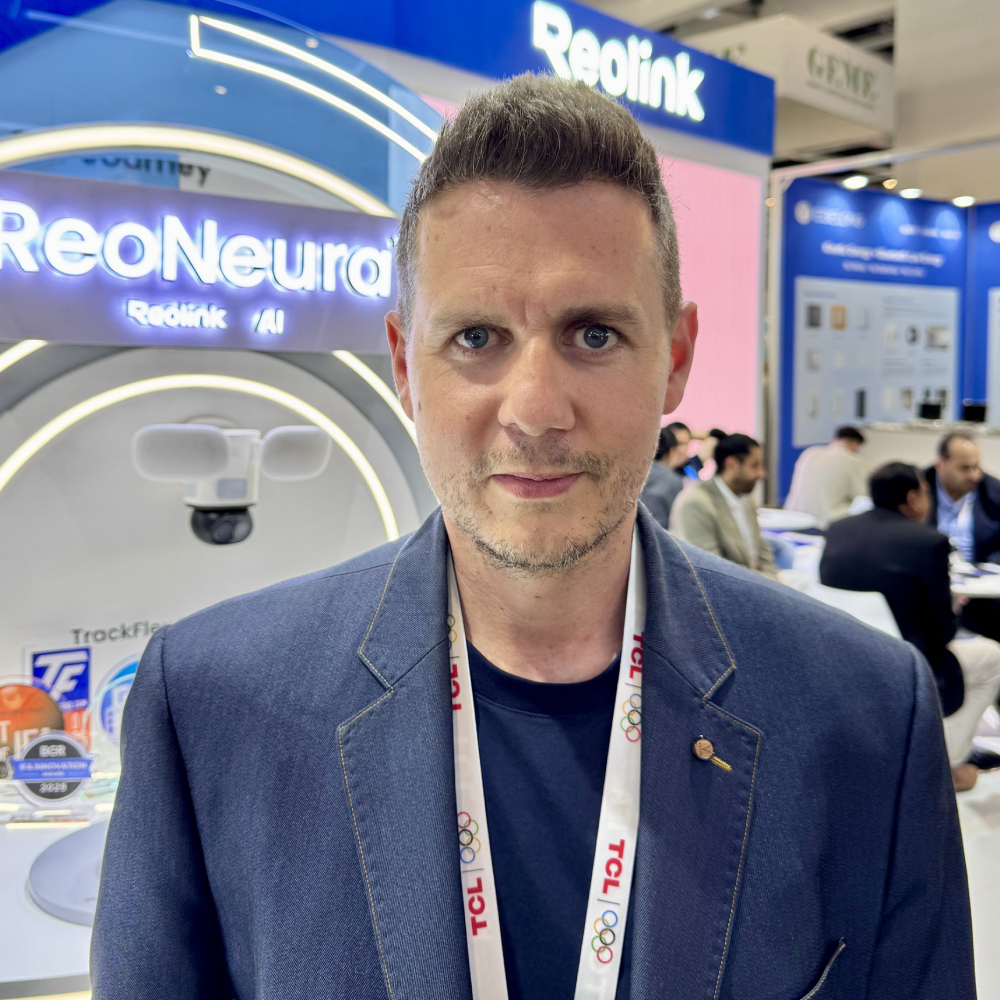male with short dark hair, blue blazer stood in exhibition venue