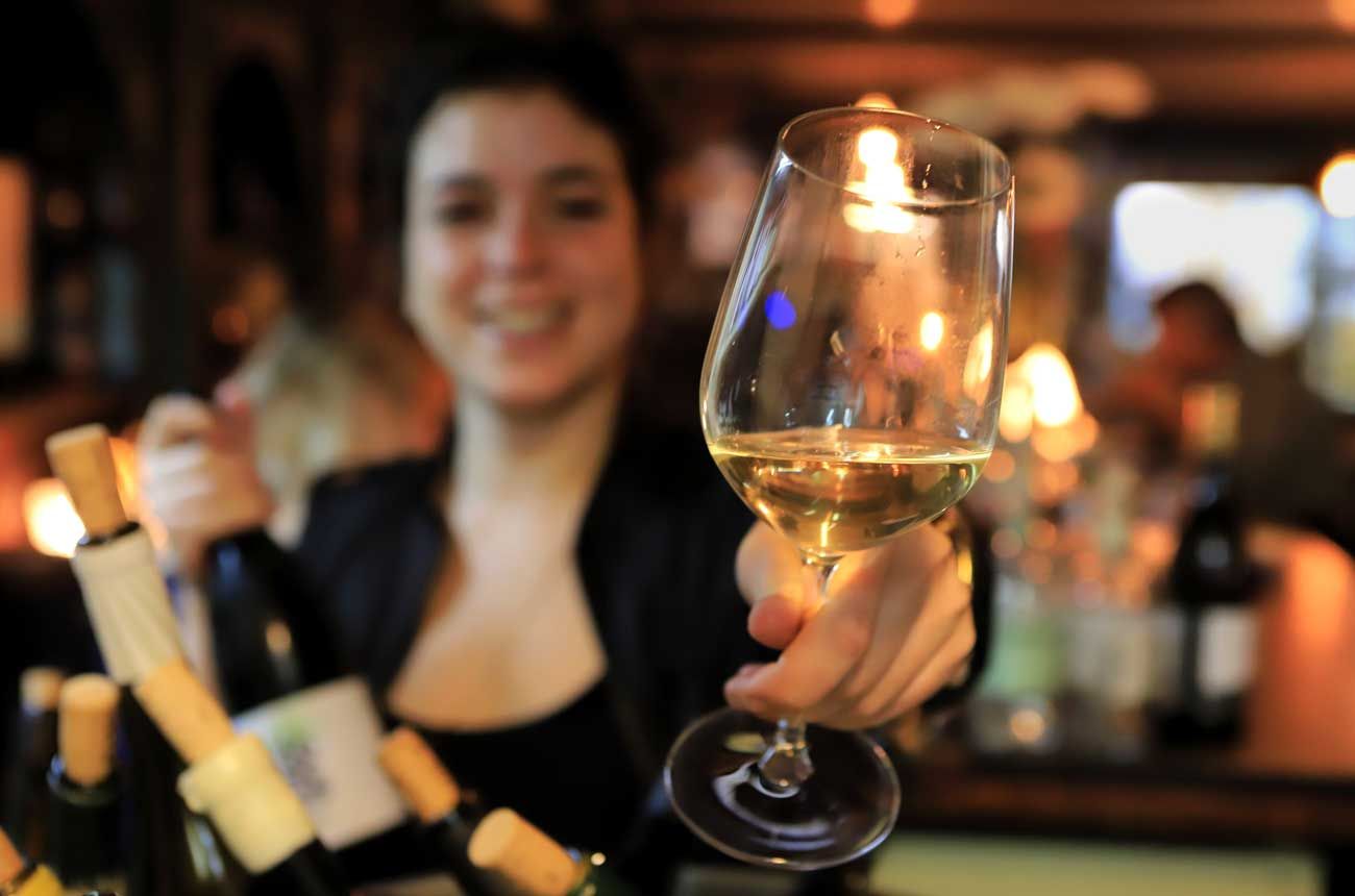 Image of a sommelier holding a wine glass for a customer.