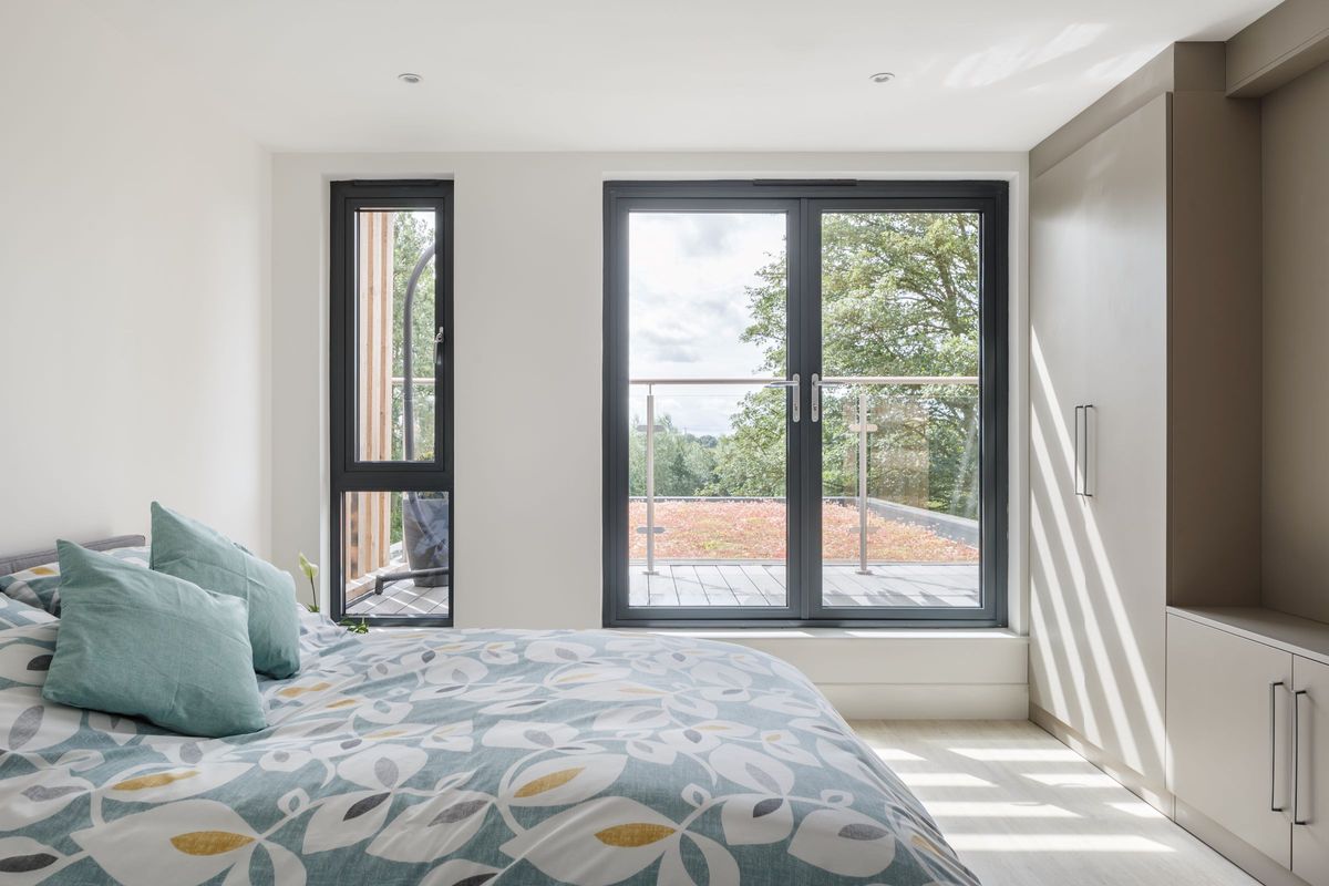 A master bedroom with multiple windows looking out onto the grounds from a large height