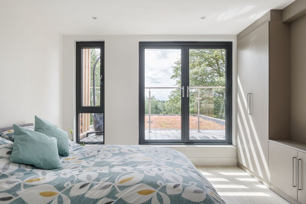 A master bedroom with multiple windows looking out onto the grounds from a large height
