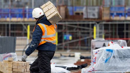 Construction worker carrying a hod of bricks