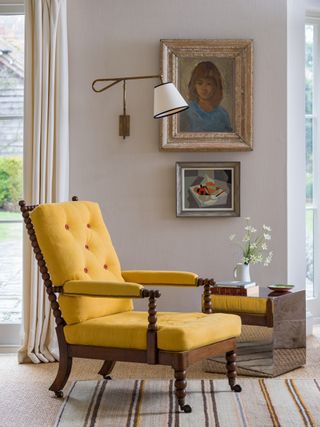 living room with yellow armchair, paintings on the wall, side table and wall light
