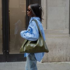 @_livmadeline wears a slouchy leather tote from Arket with a striped shirt and jeans