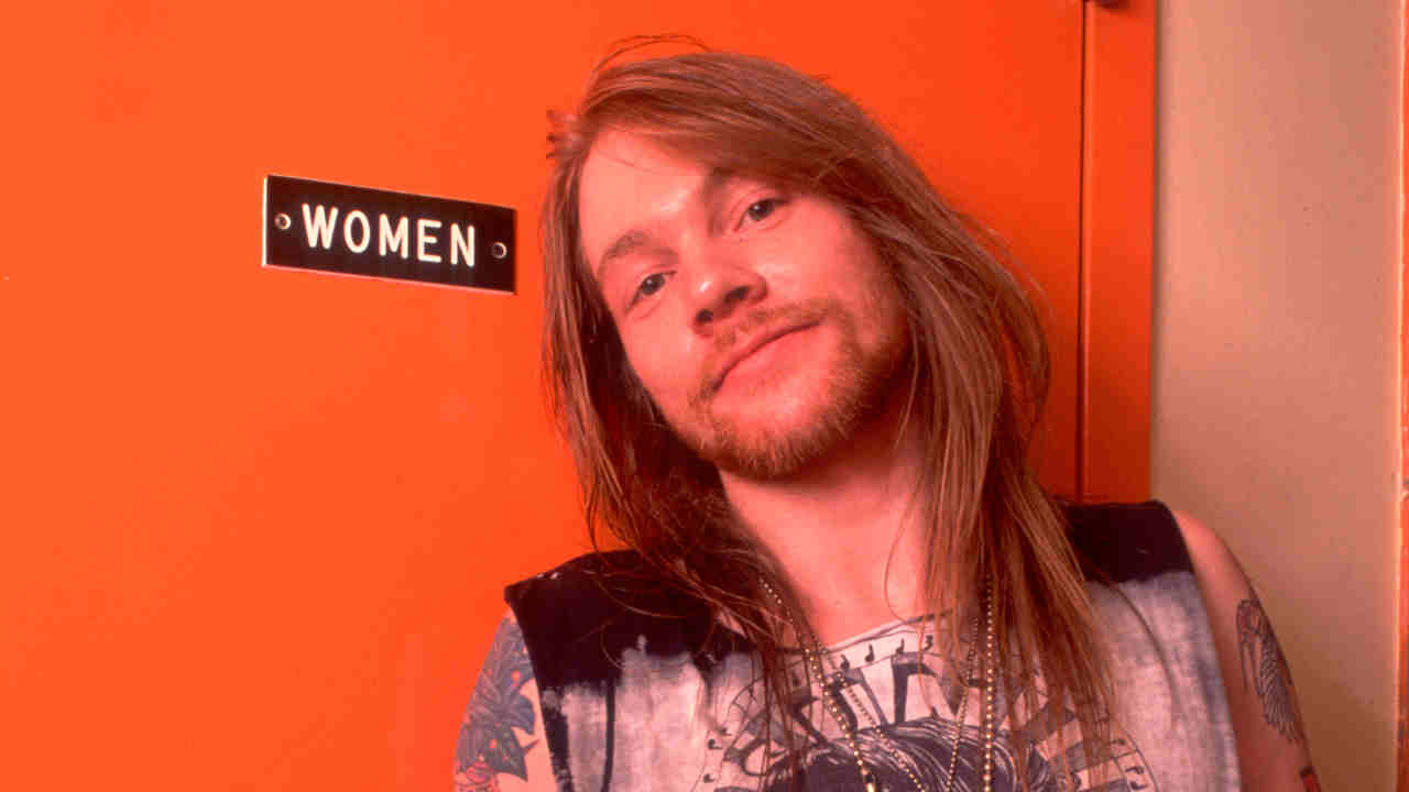 Guns N&amp;rsquo; Roses&amp;rsquo; Axl Rose posing for a photograph in front of a sign reading &amp;lsquo;Women&amp;rsquo; in 1989