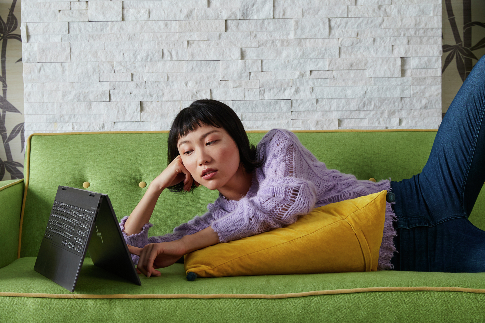 HP Envy x360 15 i en soffa med kvinna liggande bredvid.