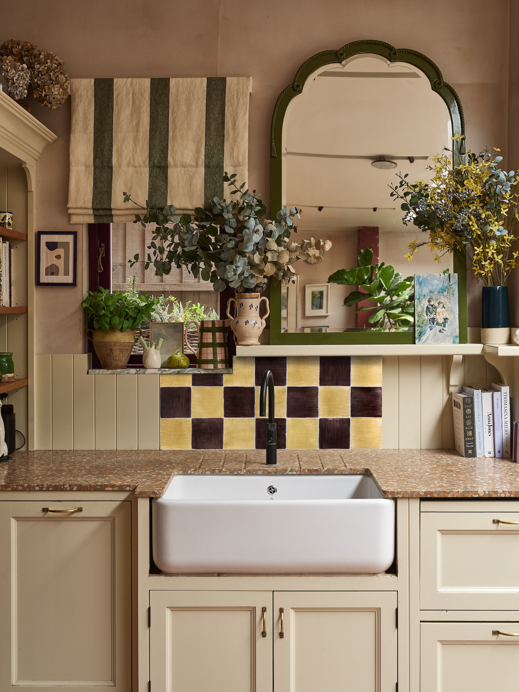 A netral and traditional kitchen sink area with a brown and butter chequerboard backsplash