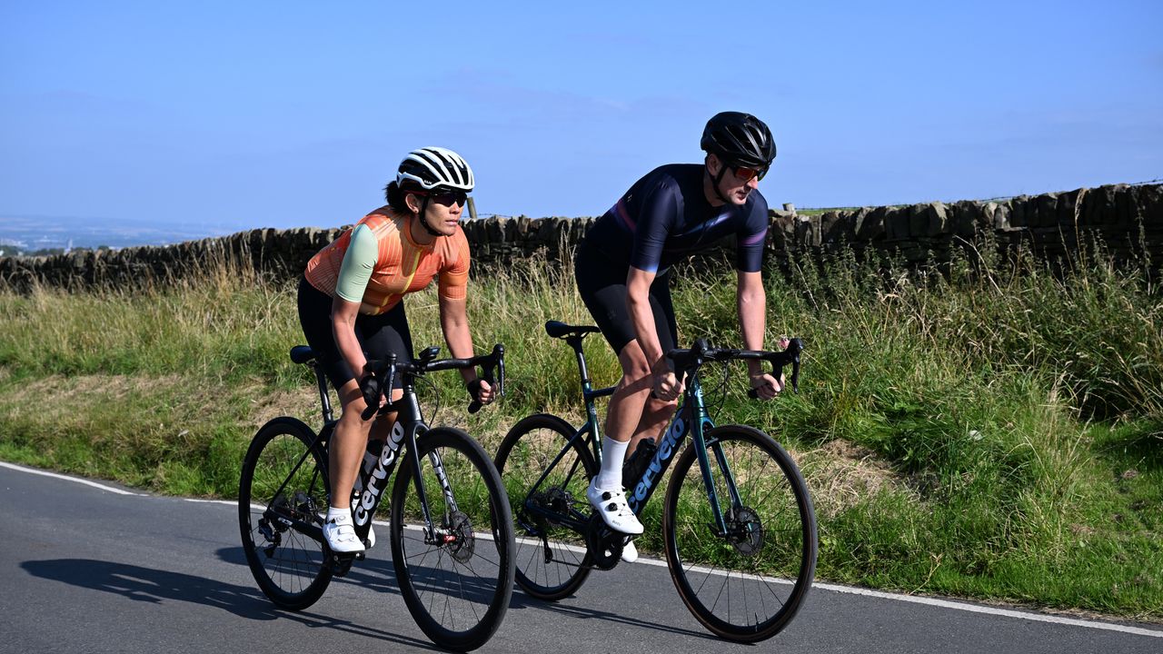 A male and female rider over 40 cycle on a sunny day