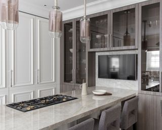 A kitchen with white cupboards and a quartzite-topped breakfast bar