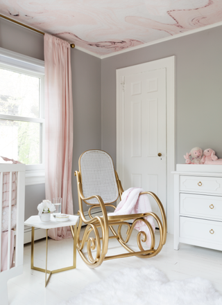 A nursery with grey pastel walls and pink pastel curtains