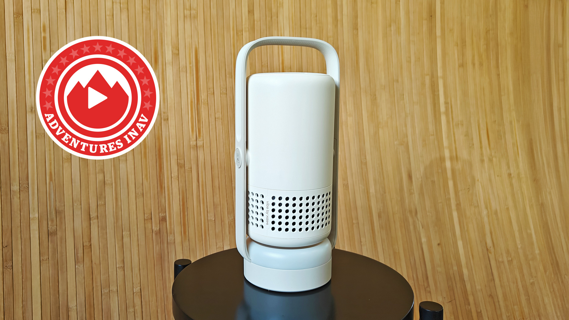 The Xgimi Vibe One projector on a black stool, with a wooden brown background.