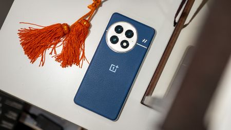 The back of the blue OnePlus 13 next to some orange tassels