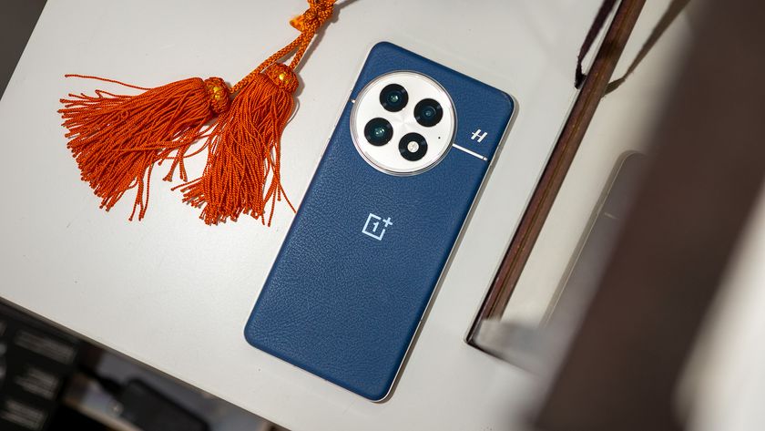 The back of the blue OnePlus 13 next to some orange tassels