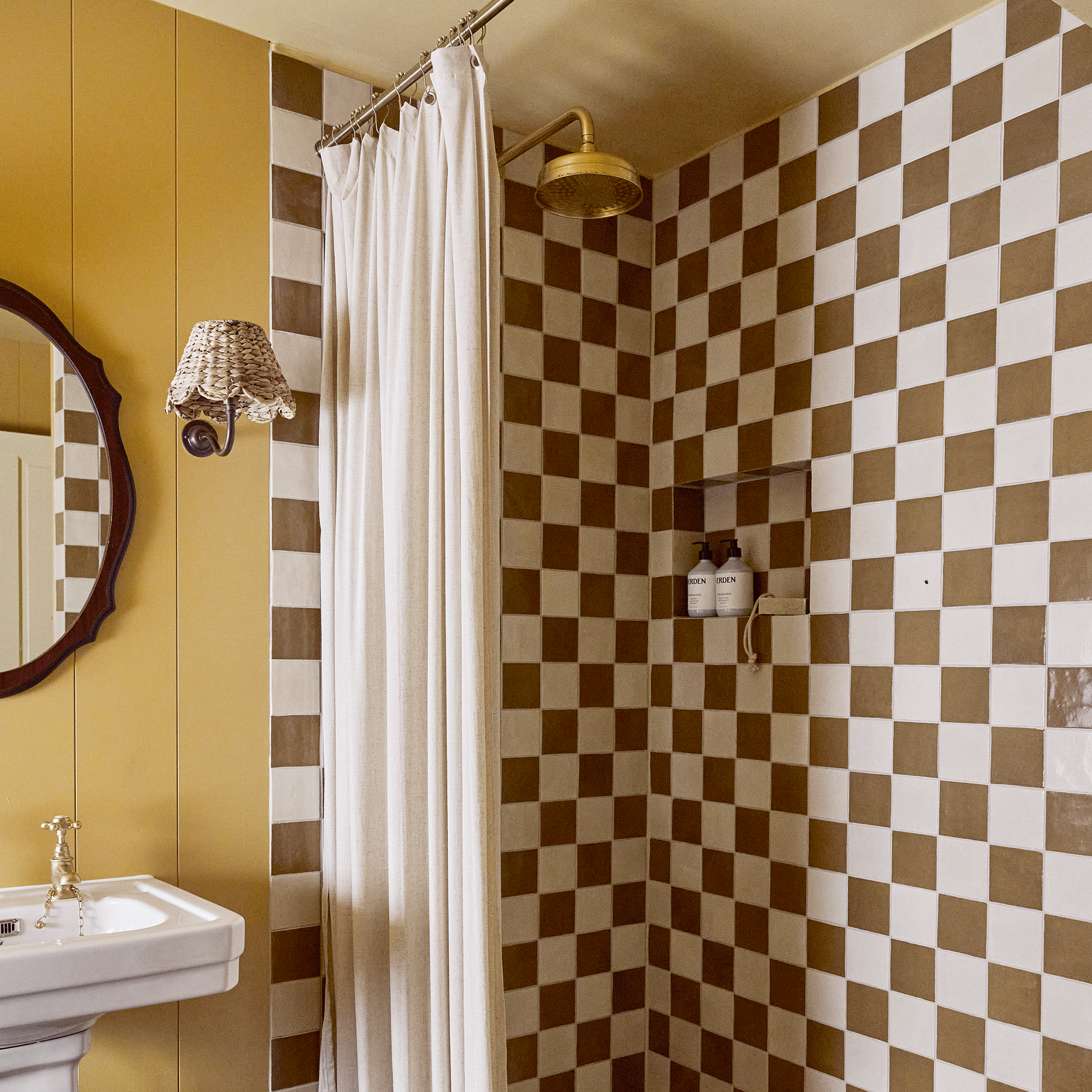 a yellow bathroom with checkered brown and cream tiles in the shower area