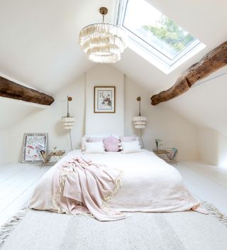 bedroom with white walls ceiling beams and pink bed throw