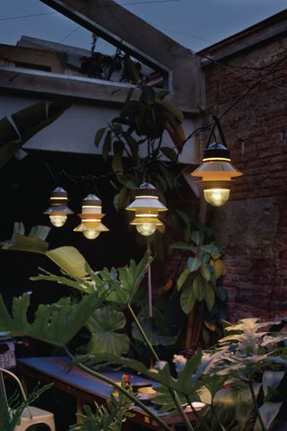 An example of patio lighting ideas showing a series of pendant lights strung up in a row